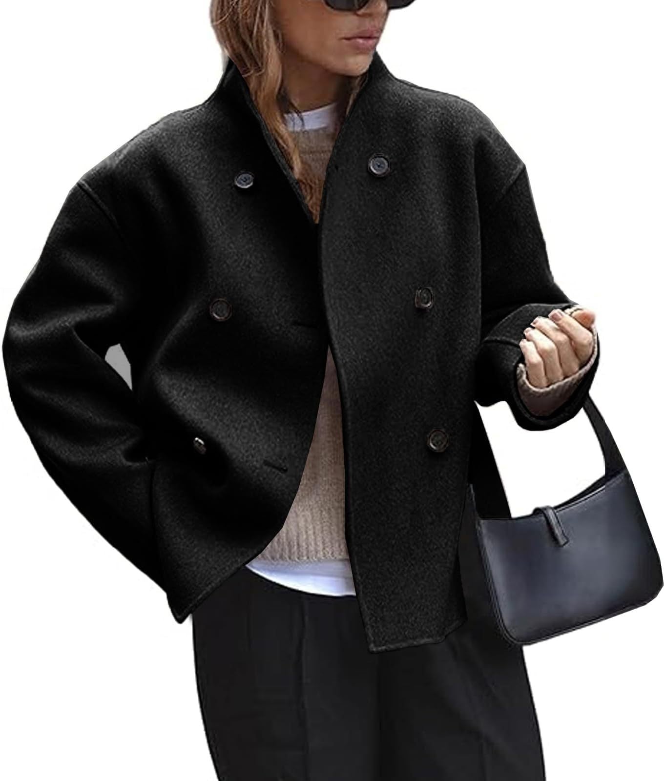 Person wearing a black coat holding a black handbag on a white background